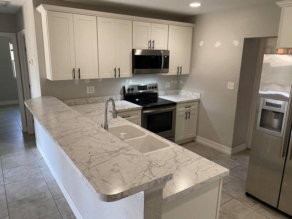 1924 Elizabeth Street Melbourne, FL 32901 - Photo 4 of 10 a kitchen with granite countertop a refrigerator and a stove top oven