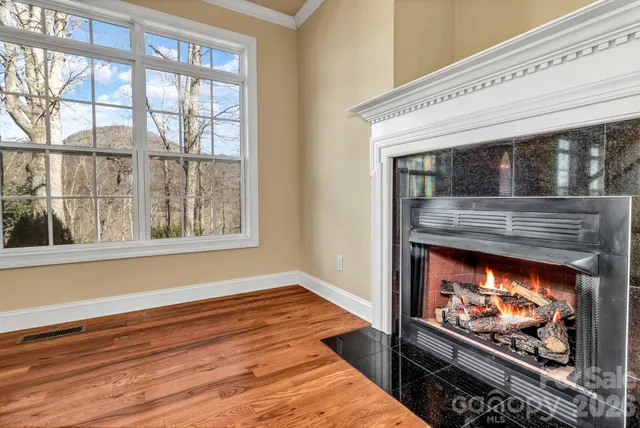 a living room with a fireplace wooden floor and a floor to ceiling window