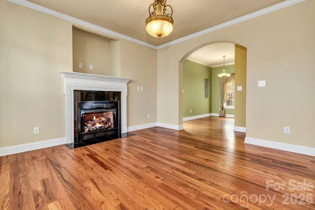 a view of an empty room with wooden floor and a fireplace