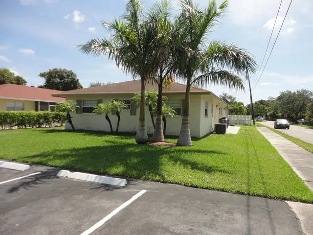 a view of a house with a yard and palm trees