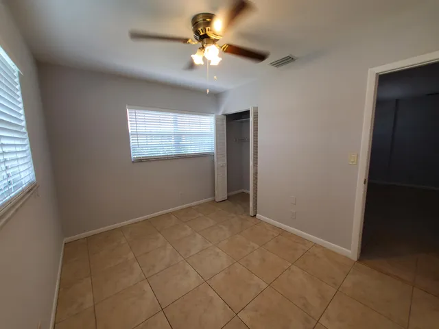 an empty room with windows and fan