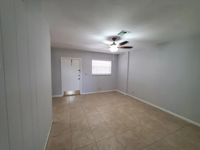 en empty room with windows and chandelier fan