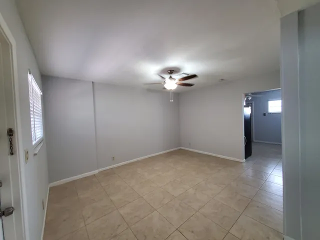an empty room with a chandelier fan and windows