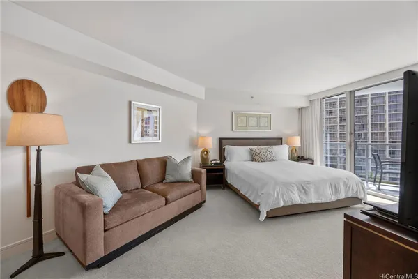 a bedroom with a bed couch and lamp next to a window
