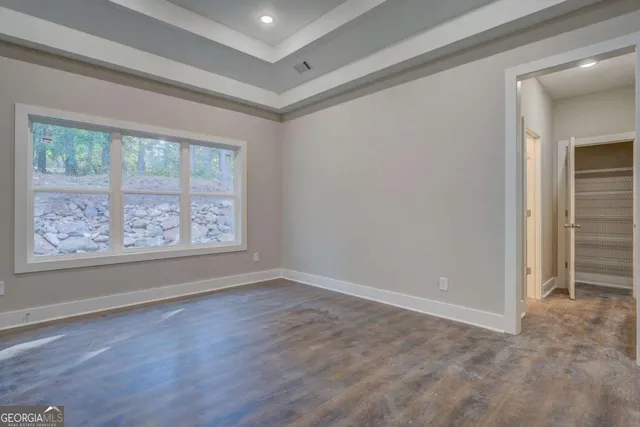 a view of an empty room with window and wooden floor