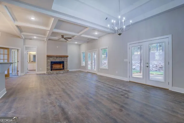 a view of an empty room with wooden floor fireplace and a window