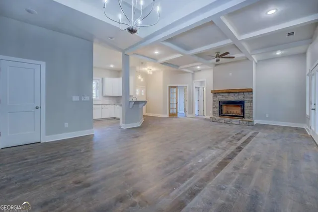 a view of an empty room with wooden floor fireplace and a window