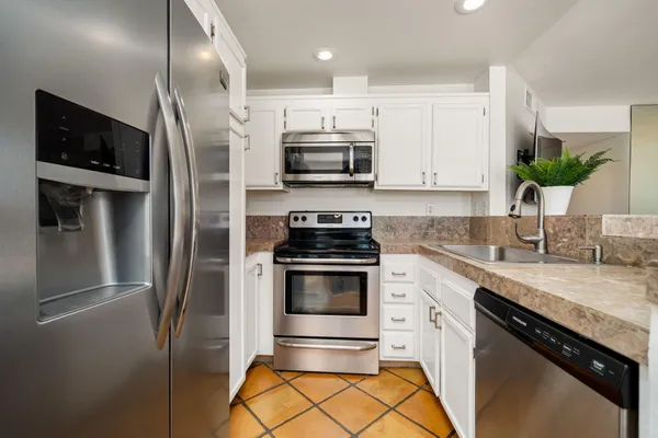 a kitchen with stainless steel appliances granite countertop a stove a refrigerator and a sink