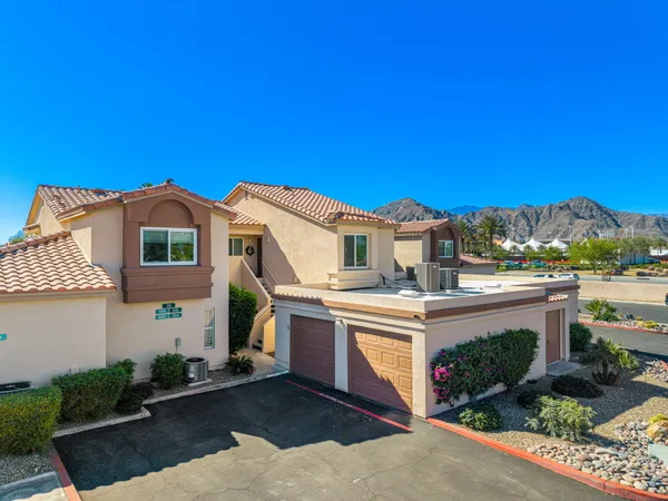 a view of a white house with a big yard and potted plants