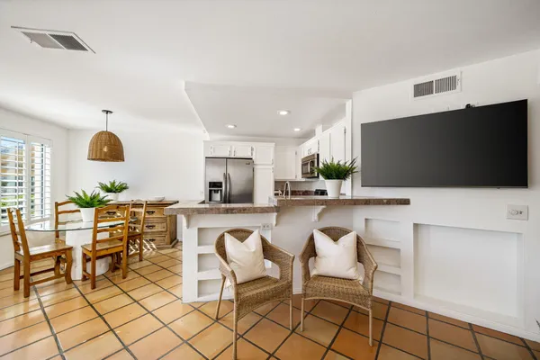 a living room with stainless steel appliances furniture and a flat screen tv