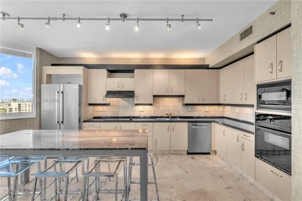a kitchen with stainless steel appliances granite countertop a stove a sink dishwasher a refrigerator and microwave with wooden floor