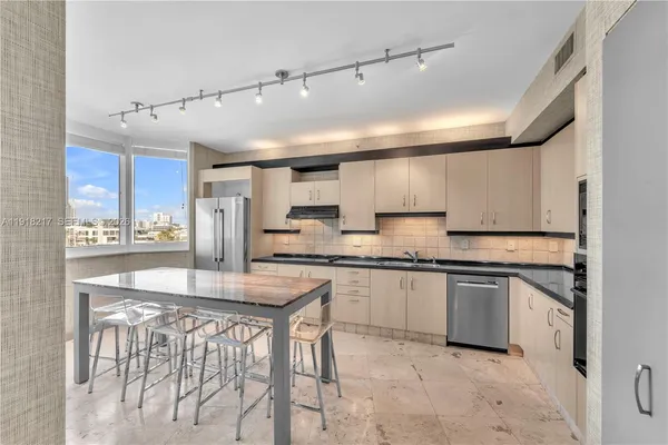 a kitchen with stainless steel appliances granite countertop a sink and a refrigerator
