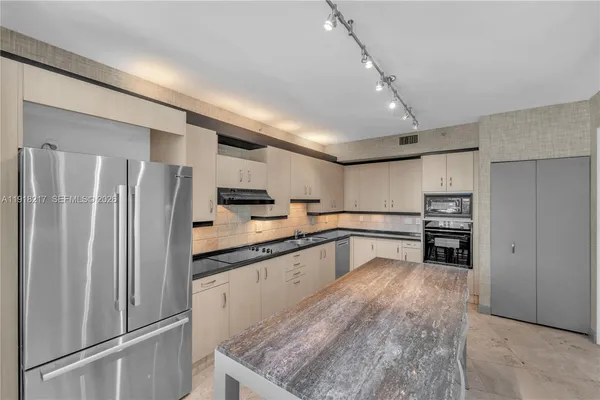 a kitchen with granite countertop a refrigerator and a sink
