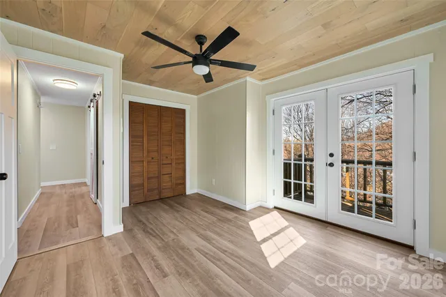 an empty room with wooden floor fan and windows