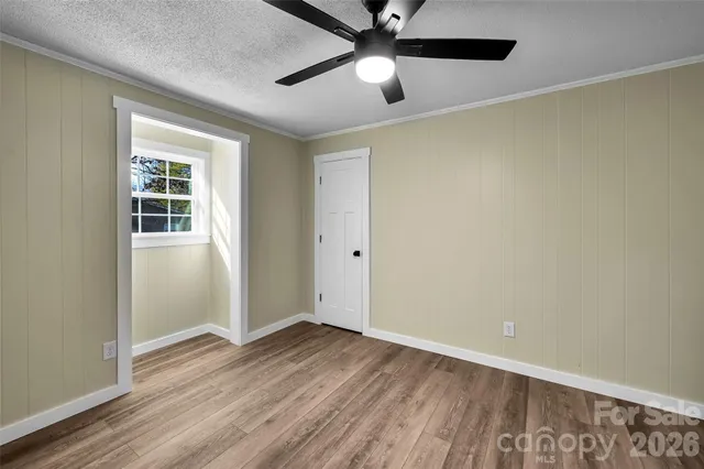 an empty room with wooden floor closet and ceiling fan