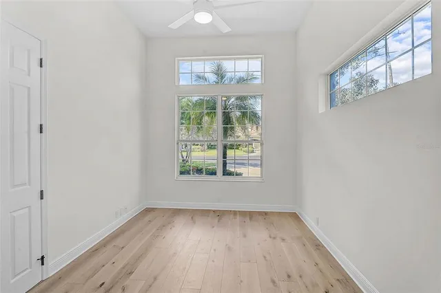an empty room with wooden floor and windows
