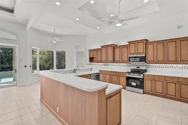 a kitchen with stainless steel appliances granite countertop a stove top oven a sink dishwasher and a refrigerator with wooden cabinets