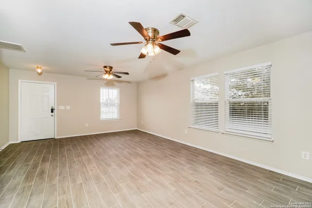 a view of an empty room with wooden floor and a window