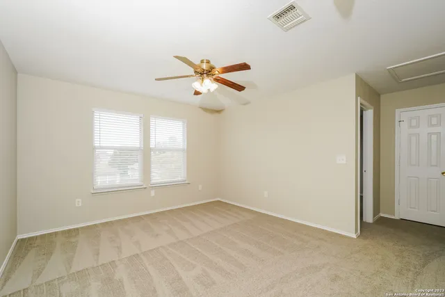 an empty room with chandelier fan and windows
