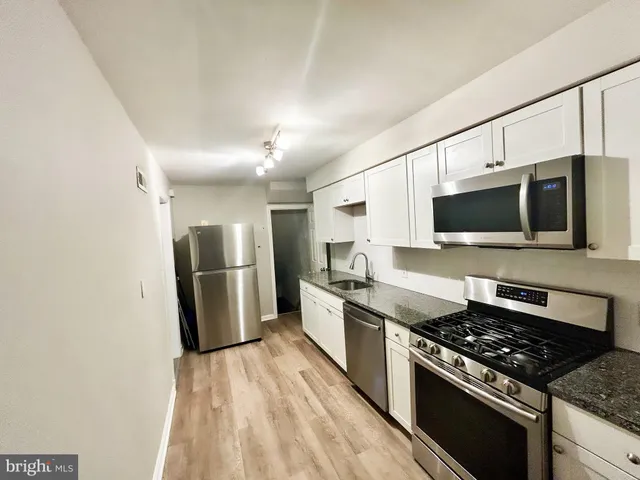 a kitchen with stainless steel appliances kitchen island granite countertop a stove and a sink
