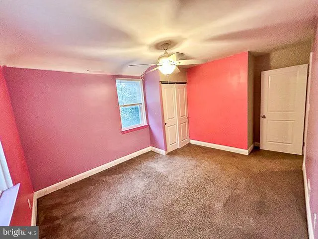 an empty room with windows and ceiling fan