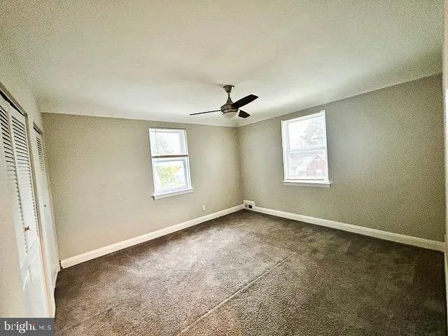 an empty room with a ceiling fan and a window