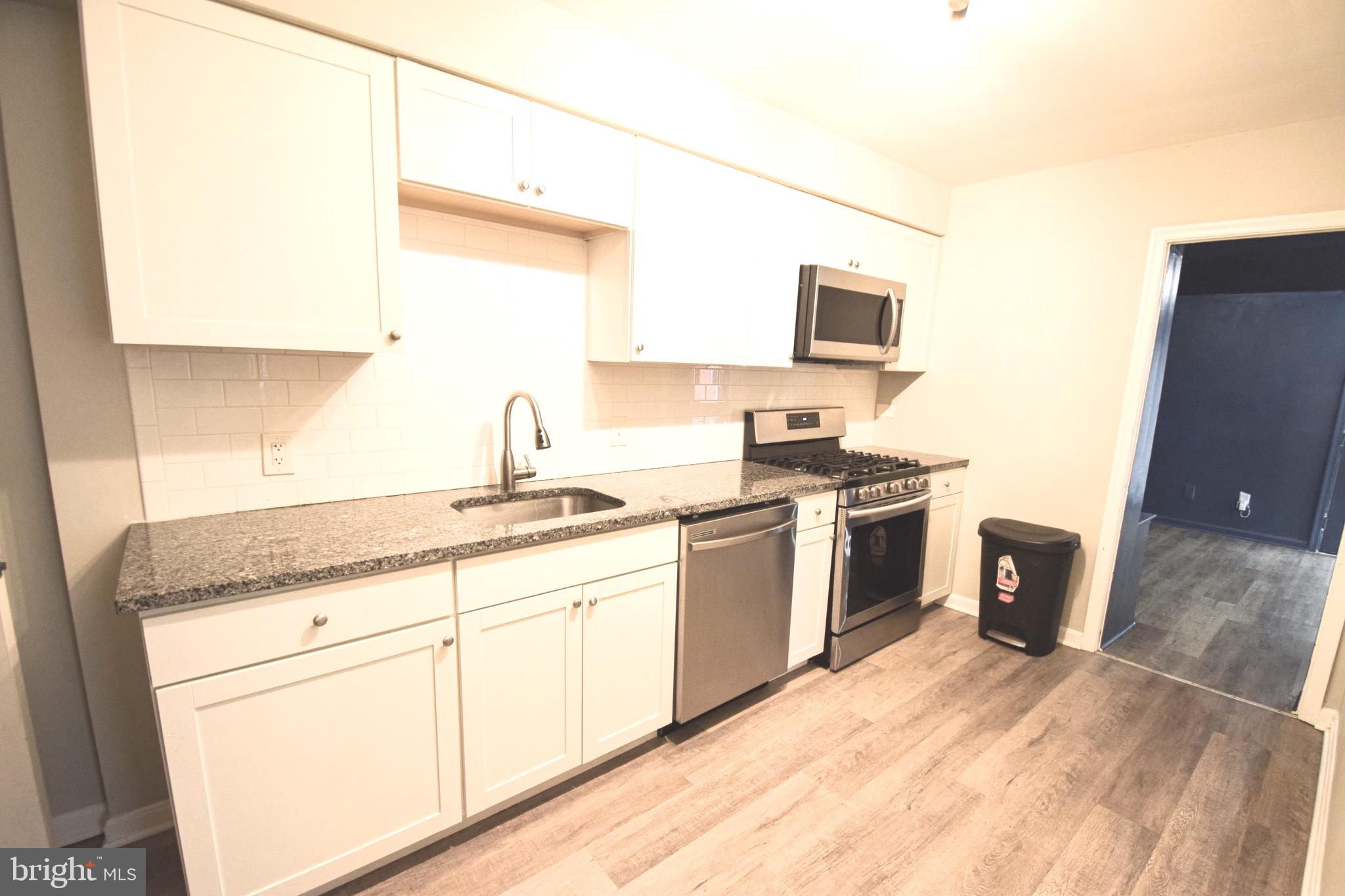 6419 Marietta Avenue Baltimore, MD 21214 - Photo 9 of 38 a kitchen with granite countertop a sink stainless steel appliances and white cabinets