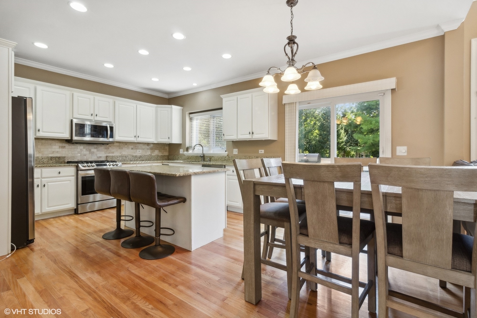 13765 Capista Drive Plainfield, IL 60544 - Photo 4 of 19 a kitchen with kitchen island granite countertop wooden floors and white cabinets