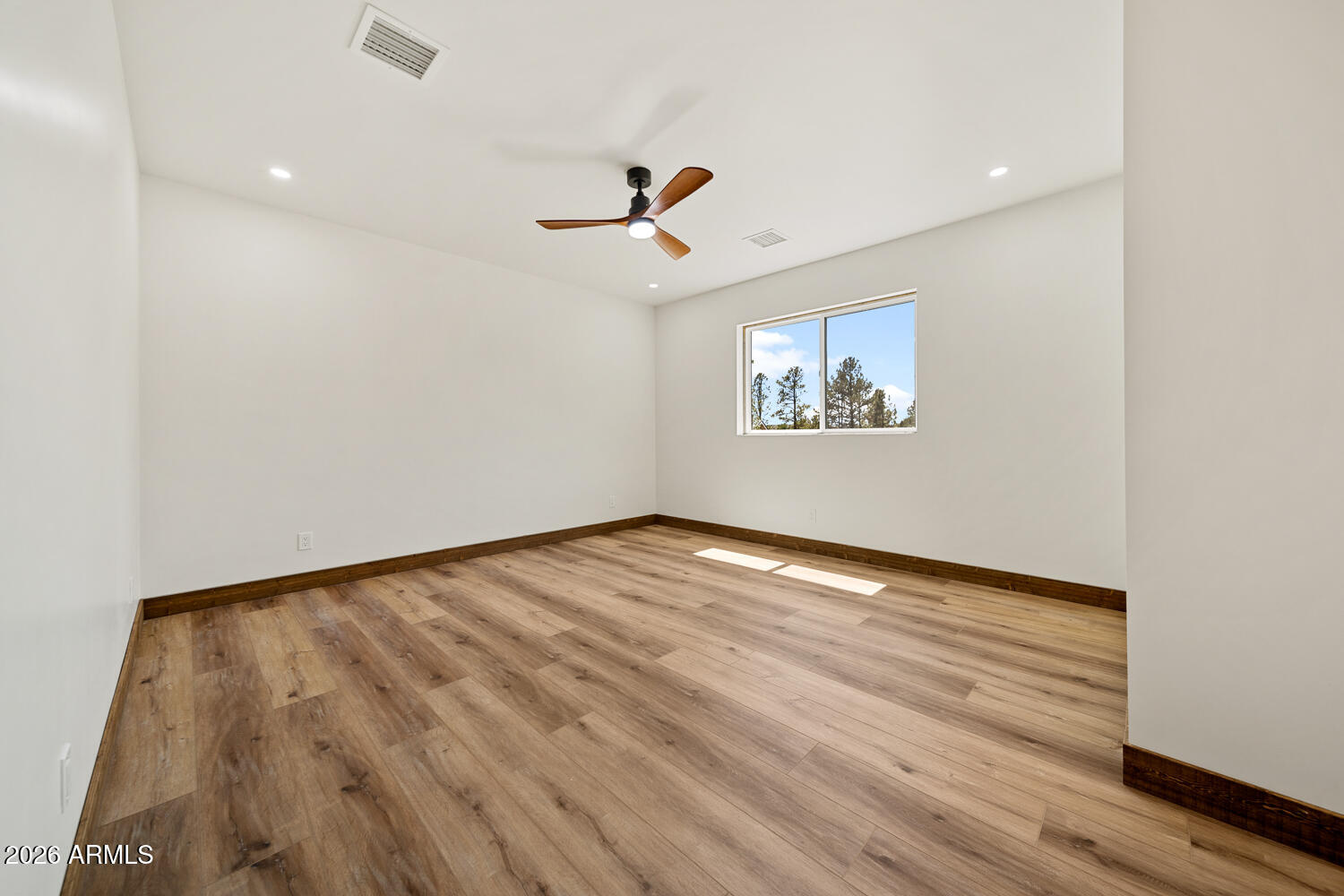 2235 Par Place Overgaard, AZ 85933 - Photo 28 of 42 an empty room with wooden floor ceiling fan and windows