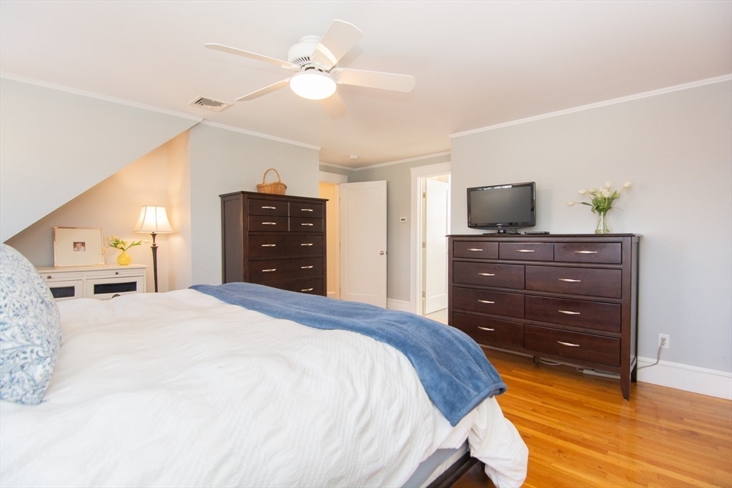 1289 Walnut Street Newton, MA 02461 - Photo 18 of 42 a bedroom with a bed a dresser and a flat screen tv