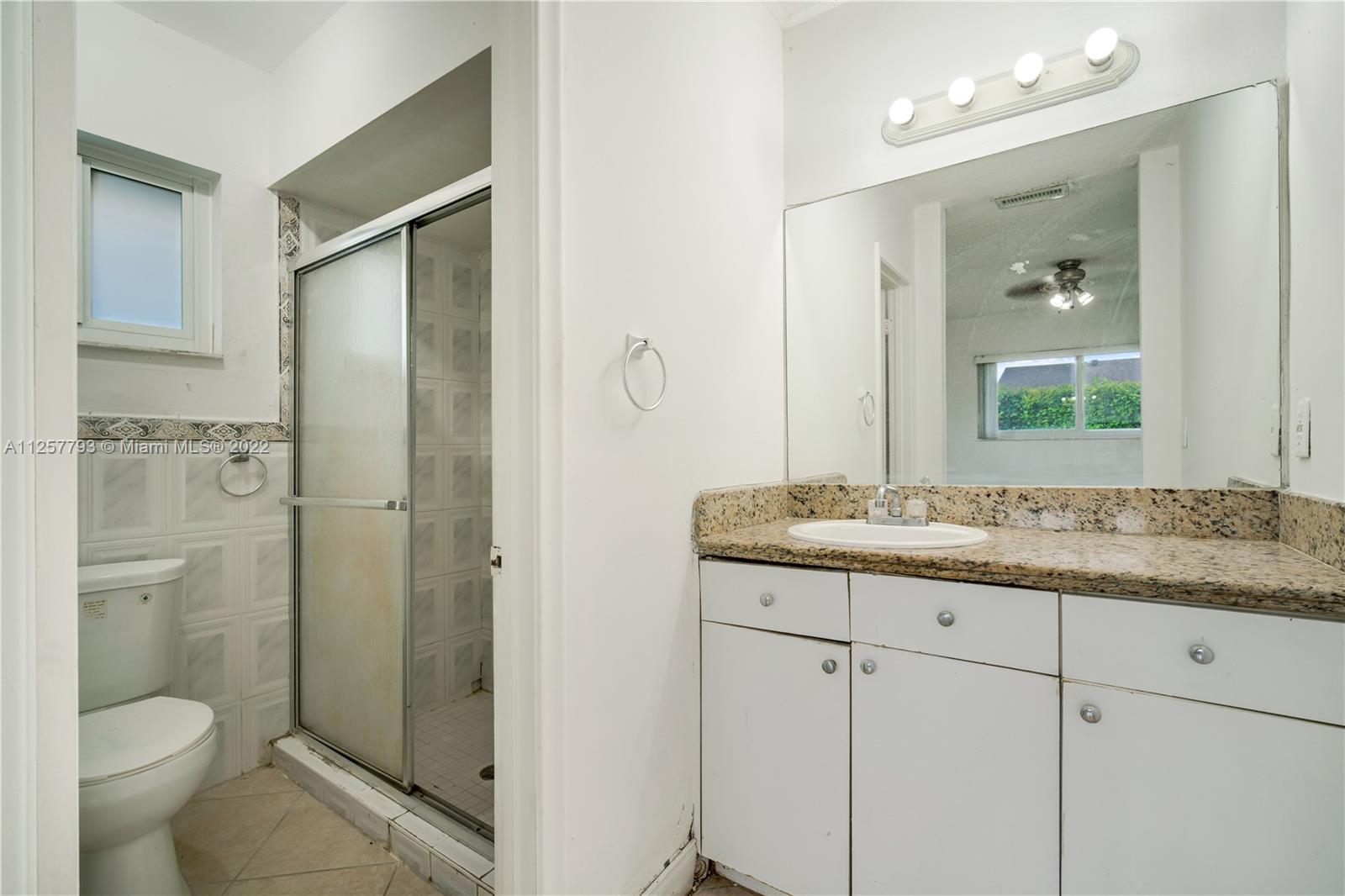 14121 Southwest 47th Street Miami, FL 33175 - Photo 24 of 45 a bathroom with a granite countertop toilet sink and shower