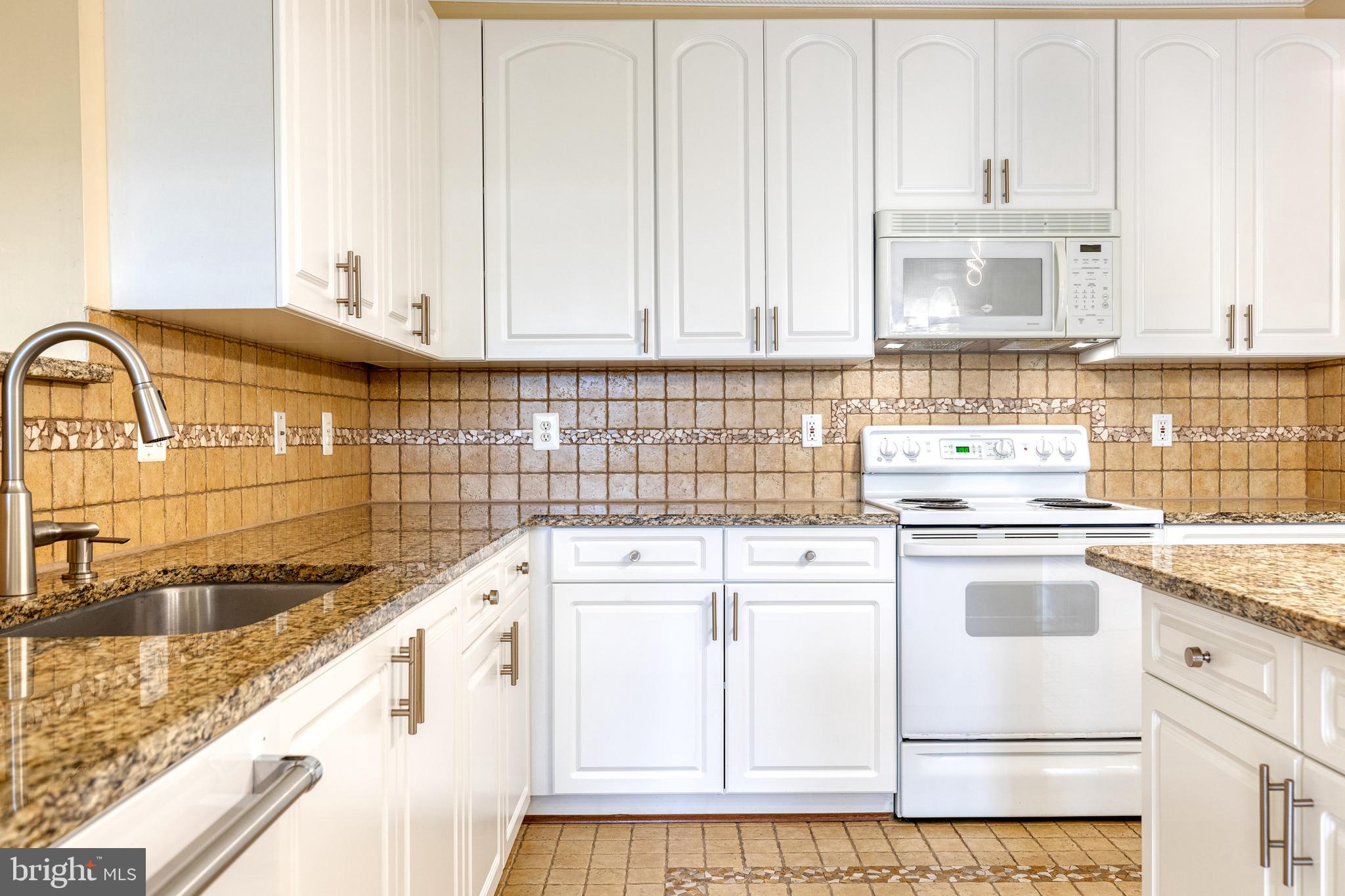 400 Symphony Circle, Unit 406 Hunt Valley, MD 21030 - Photo 14 of 37 a kitchen with granite countertop white cabinets and white appliances
