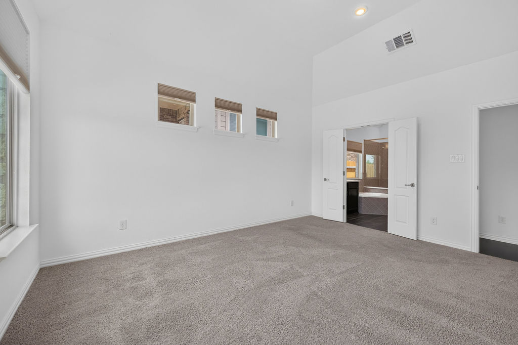 1332 Ridge Runner Drive Georgetown, TX 78628 - Photo 20 of 40 A spacious primary bedroom features soft carpeting, lofty vaulted ceilings, and a private en-suite bathroom.