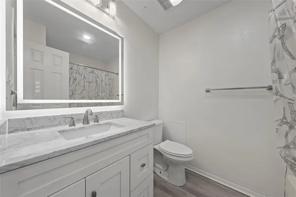 a bathroom with a granite countertop sink a toilet and a mirror