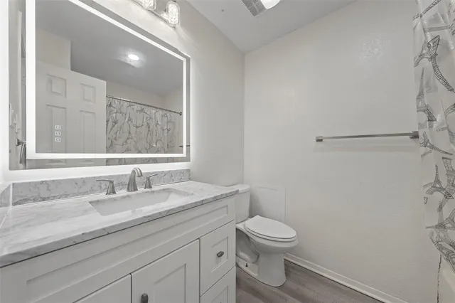 a bathroom with a granite countertop sink a toilet and a mirror