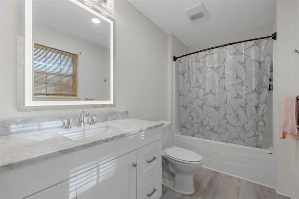 a bathroom with a granite countertop sink a toilet and shower