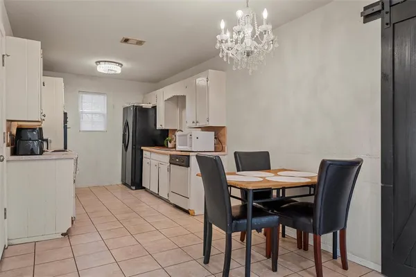 a kitchen with a dining table chairs and refrigerator
