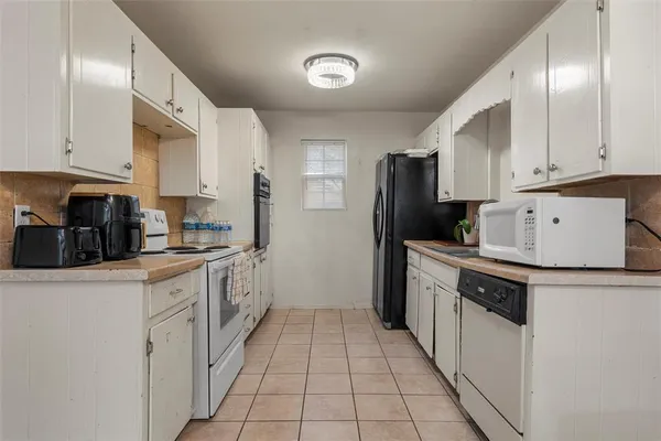 a kitchen with a sink a stove top oven and white cabinets