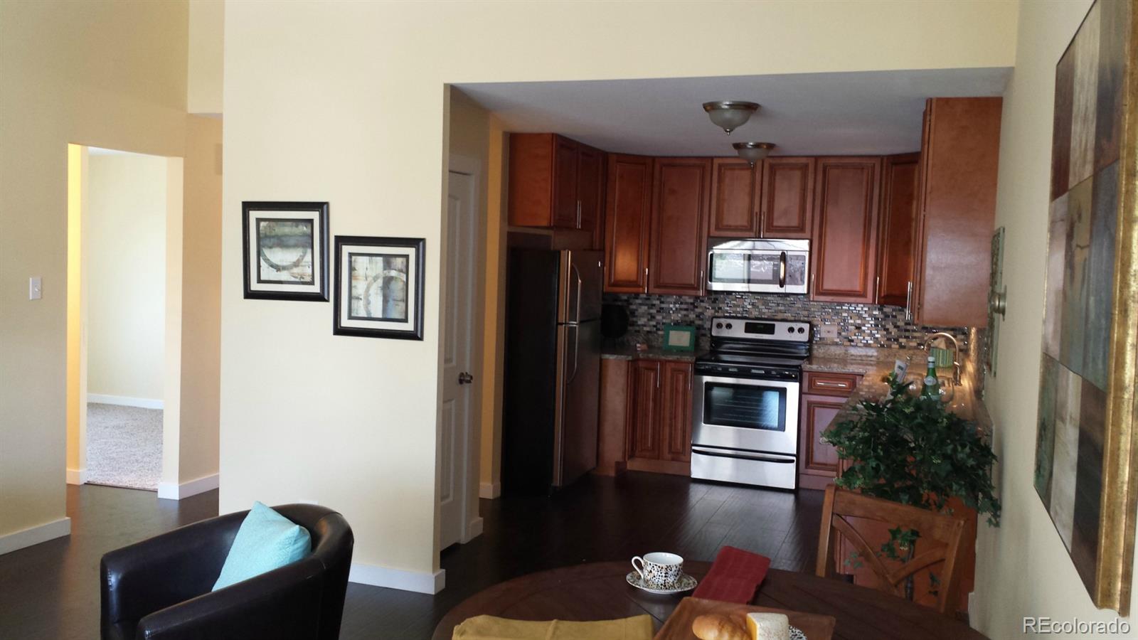 615 South Clinton Street, Unit 9B Denver, CO 80247 - Photo 1 of 1 a kitchen with granite countertop stainless steel appliances and wooden cabinets