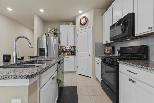a kitchen with microwave a refrigerator and chairs