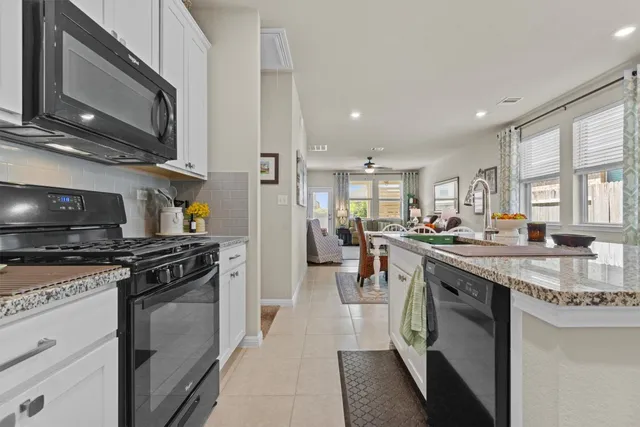 a kitchen with stainless steel appliances granite countertop a stove top oven a sink dishwasher and a refrigerator
