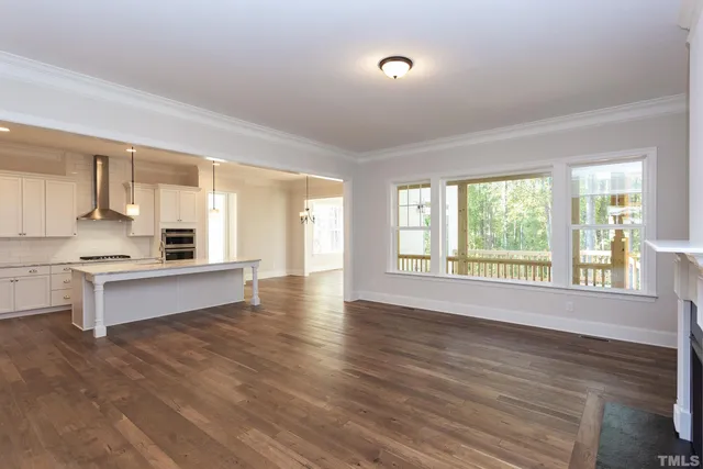 a kitchen with a stove a sink a kitchen island with wooden floor cabinets and chairs