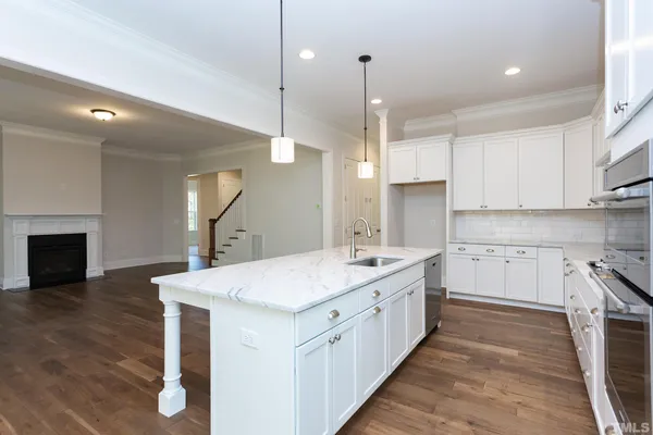 a kitchen with stainless steel appliances kitchen island granite countertop a stove a sink and white cabinets with wooden floor
