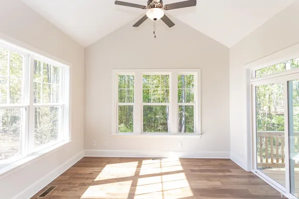 an empty room with a ceiling fan and windows