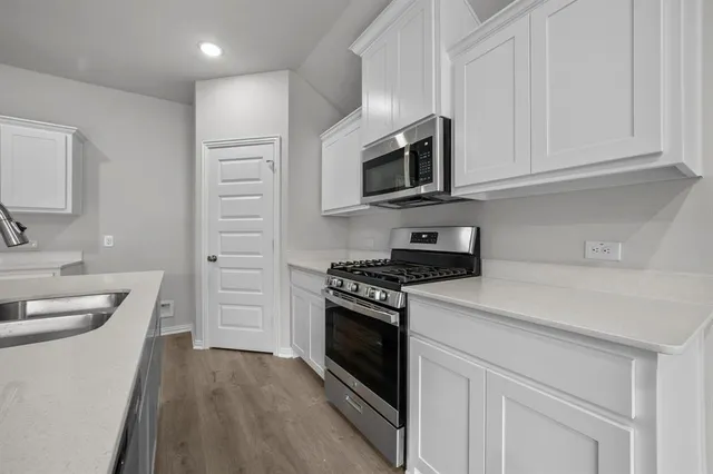 a kitchen with stainless steel appliances granite countertop a stove microwave and sink