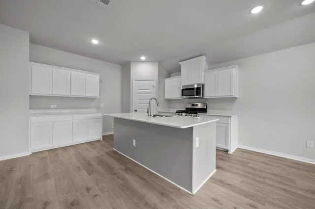 a kitchen with granite countertop white cabinets and black stainless steel appliances