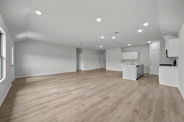 a view of kitchen with kitchen island a sink wooden floor and a refrigerator