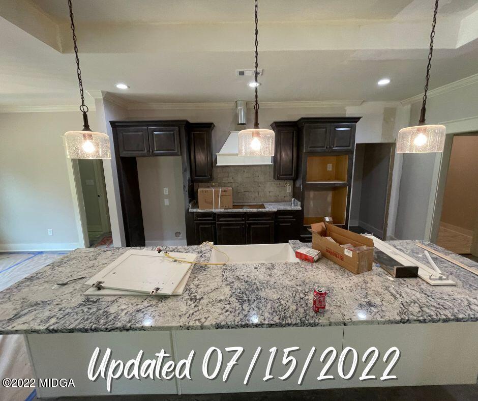 411 Stonegate Trail Perry, GA 31069 - Photo 5 of 14 a kitchen with kitchen island granite countertop a refrigerator and a sink
