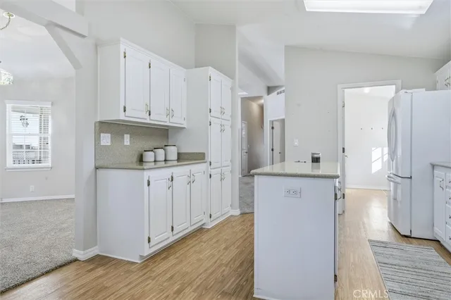 a kitchen with white cabinets and refrigerator