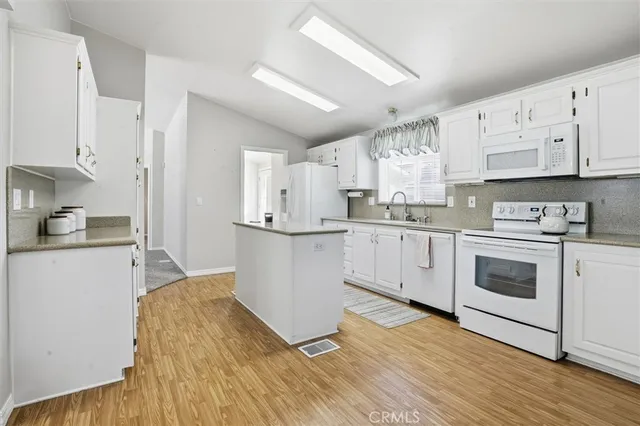 a kitchen with granite countertop white cabinets and white appliances